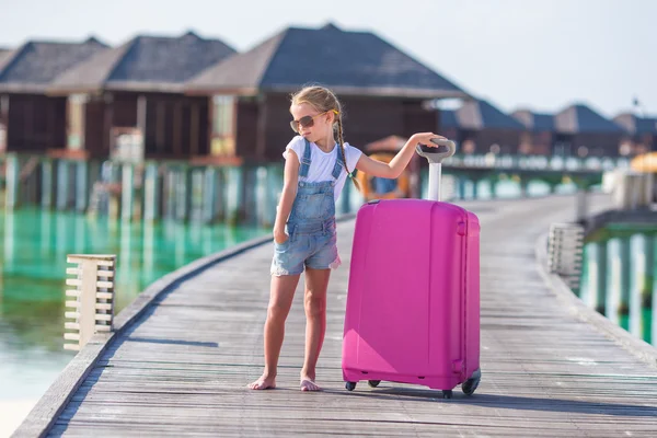 Petite adorable fille avec de gros bagages sur une jetée en bois sur le chemin du bungalow d'eau pendant les vacances d'été — Photo