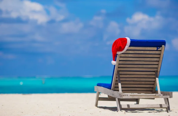 Red Santa hat on chair longue at tropical white beach — стоковое фото
