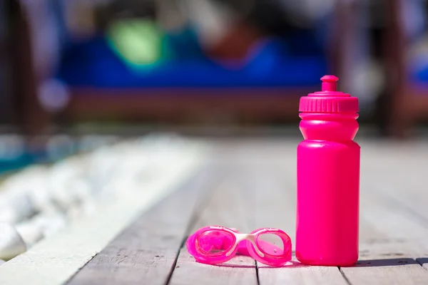 Botella de agua deportiva rosa cerca de la piscina — Foto de Stock