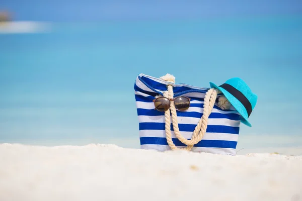 Plaj aksesuarları - mavi çanta, hasır şapka, güneş gözlüğü beyaz plaj üzerinde — Stok fotoğraf