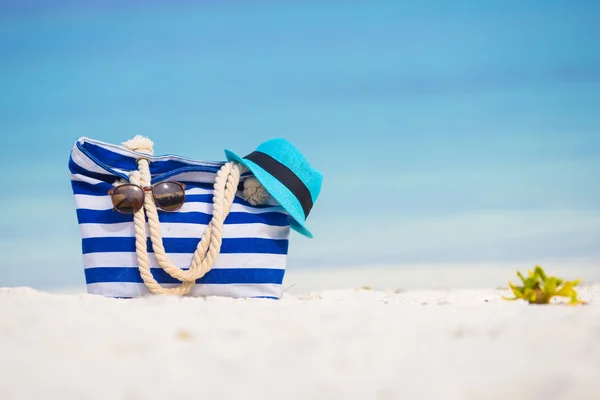 Plaj aksesuarları - mavi çanta, hasır şapka, güneş gözlüğü beyaz plaj üzerinde — Stok fotoğraf