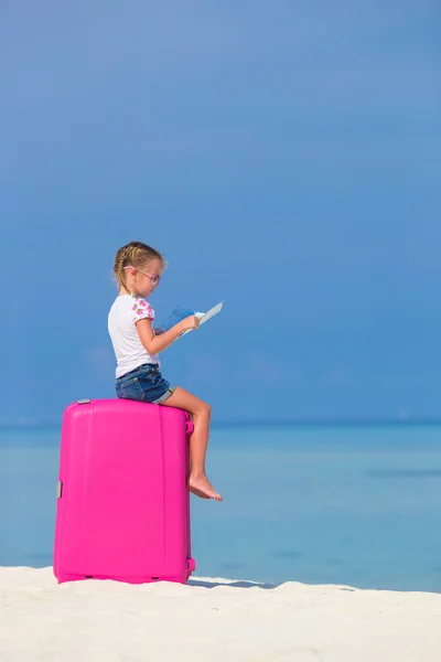 Little adorable girl with big pink suitcase and map of island on white beach — Stock Photo, Image