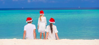 Üç Noel Baba şapkaları sahilde içinde mutlu aile