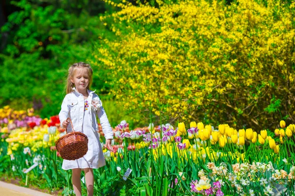 Frühlingsgarten, Frühlingsblumen, liebenswertes kleines Mädchen und Tulpen — Stockfoto