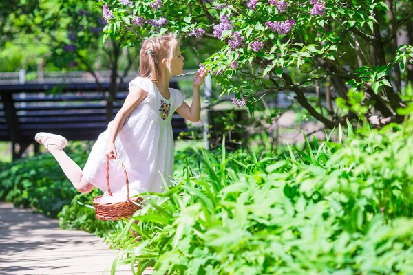 ライラックの花庭でバスケットのかわいい幸せな女の子 — ストック写真