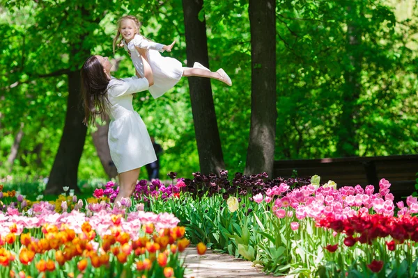 Mãe feliz e menina adorável no jardim tulipa — Fotografia de Stock