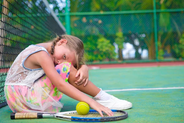 Niña tratando de jugar al tenis en la cancha al aire libre —  Fotos de Stock