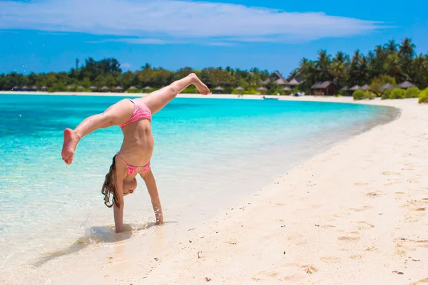 Rozkošný šťastná holčička se bavit v mělké vodě na pláži dovolenou — Stock fotografie