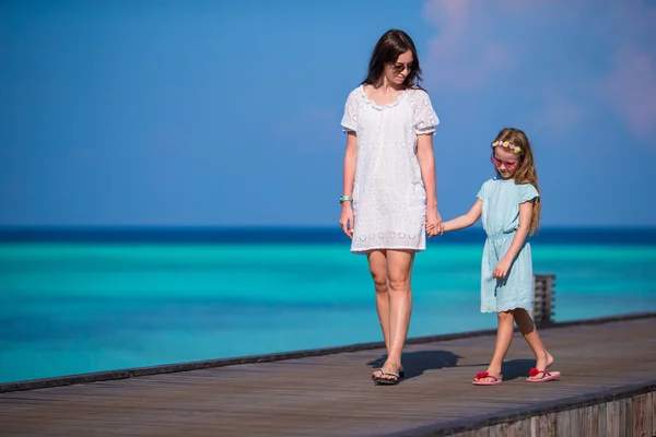 Bambina e giovane madre che camminano su un molo di legno in un resort esotico — Foto Stock