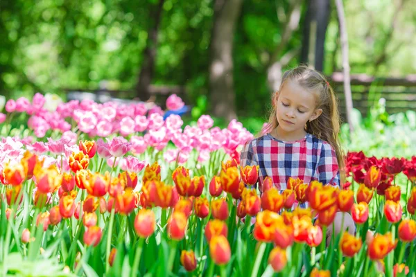 Kleines entzückendes Mädchen im üppigen Garten der Tulpen — Stockfoto