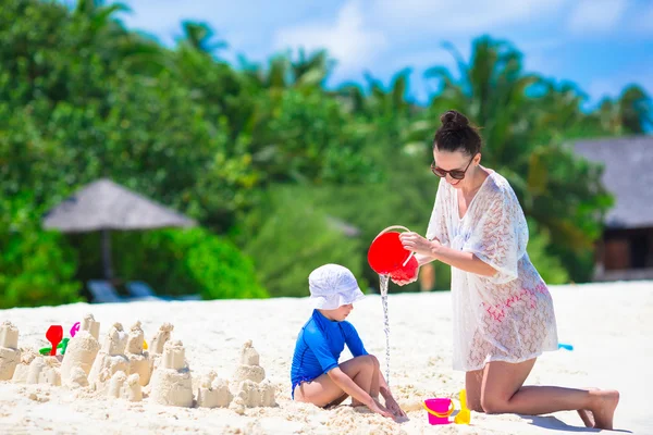 Niña y mamá joven jugando con juguetes de playa en vacaciones tropicales — Foto de Stock