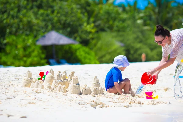 Malá holka a mladí máma hraje s hračkami, pláž na tropickou dovolenou — Stock fotografie