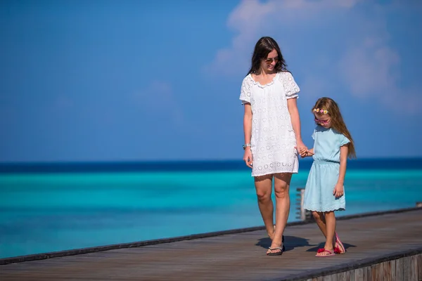 Little girl and young mother walking on wooden jetty at exotic resort — Stock Photo, Image