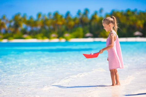 Schattig meisje spelen met origami boot in de turquoise zee — Stockfoto