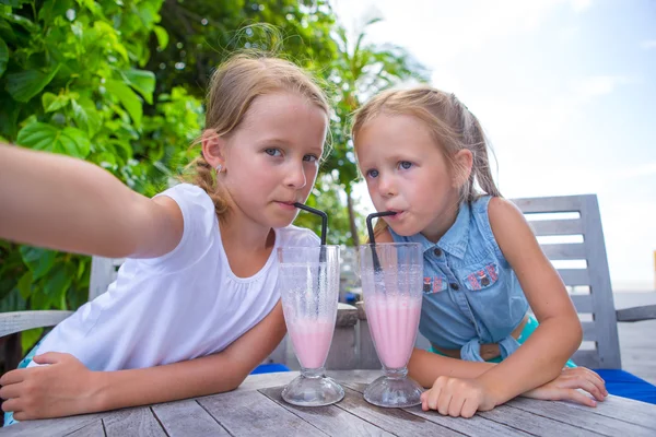 Little girls taking selfie and drinking tasty cocktails at outdoor cafe — Stock Photo, Image