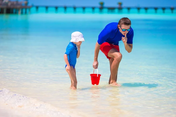 Pai e menina pegando peixes na praia tropical — Fotografia de Stock