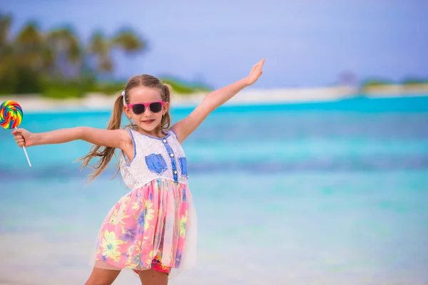 Adorable niña con piruleta en vacaciones en la playa tropical —  Fotos de Stock