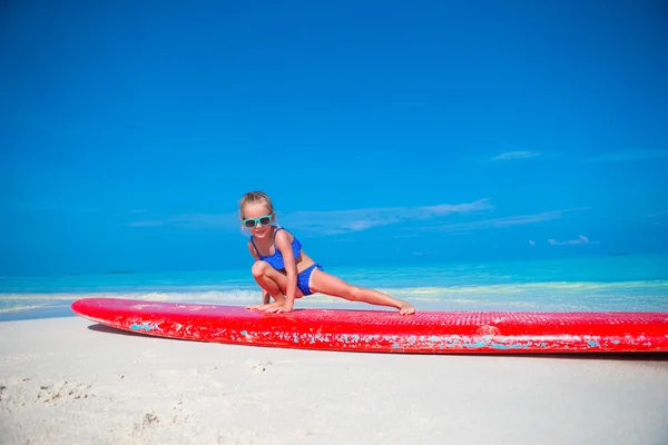 Niña adorable en una tabla de surf en el mar turquesa —  Fotos de Stock