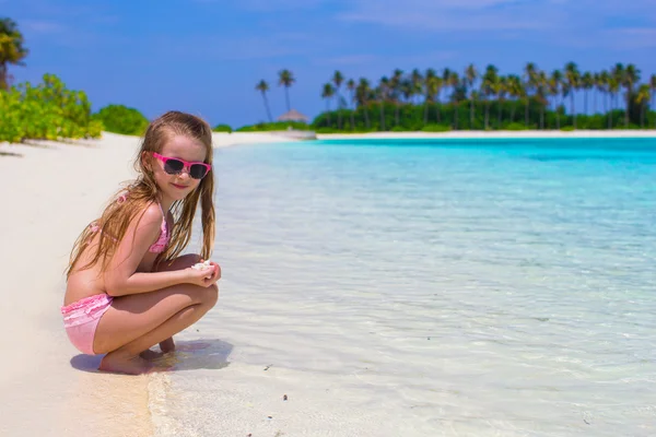 Malá holčička baví na tropické pláži tyrkysové moře vodou — Stock fotografie