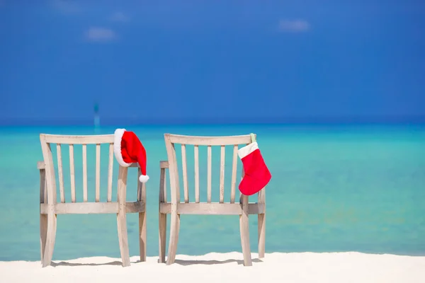 Calze rosse di Natale e Santa Hat sulla sedia sulla spiaggia tropicale bianca — Foto Stock