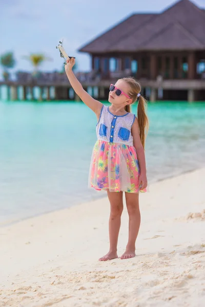 Fetiță fericită cu avion de jucărie în mâini pe plaja cu nisip alb — Fotografie, imagine de stoc