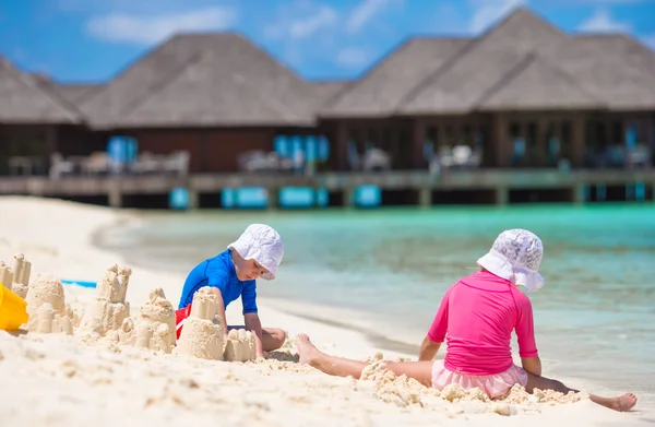 Duas crianças fazendo castelo de areia e brincando na praia tropical — Fotografia de Stock