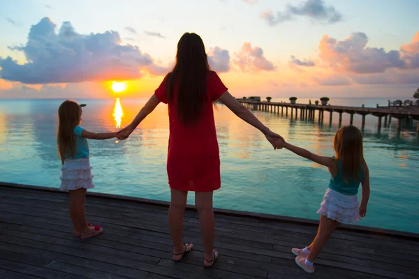 Silueta de madre joven y dos de sus niñas al atardecer — Foto de Stock