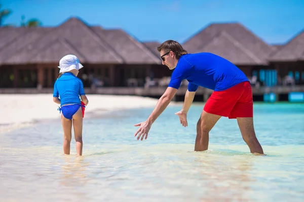 Батько і маленька дівчинка ловить рибу на тропічному пляжі — стокове фото