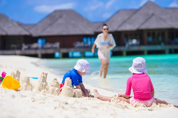 Duas meninas e mãe feliz brincando com brinquedos de praia nas férias de verão — Fotografia de Stock