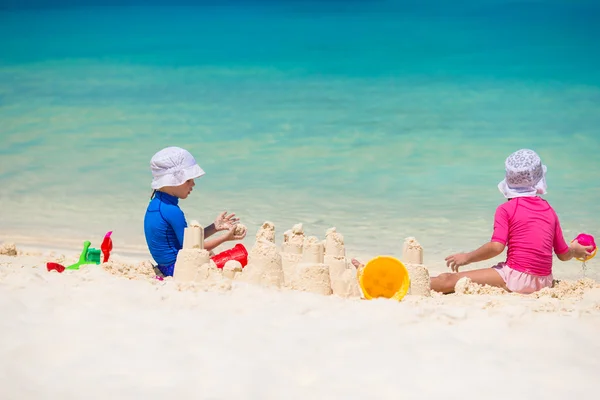 Dos niños haciendo castillo de arena y jugando en la playa tropical — Foto de Stock