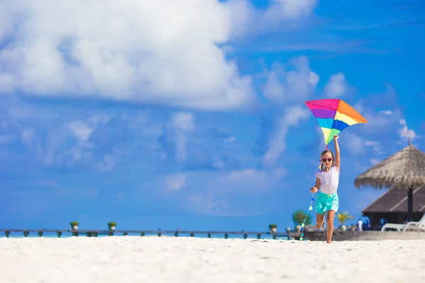 Pequena menina feliz brincando com pipa voadora na praia tropical — Fotografia de Stock