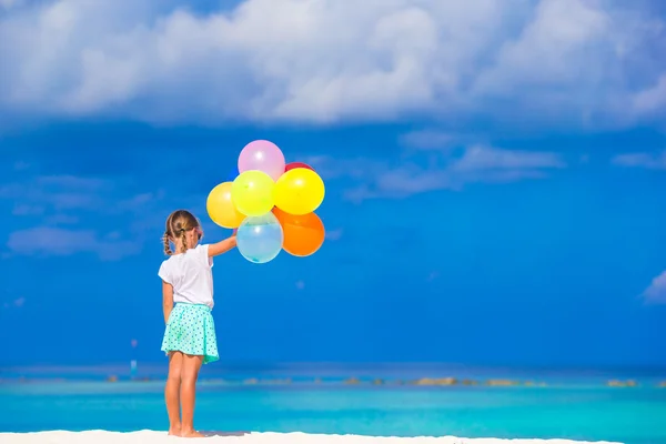 Adorável menina brincando com balões na praia — Fotografia de Stock