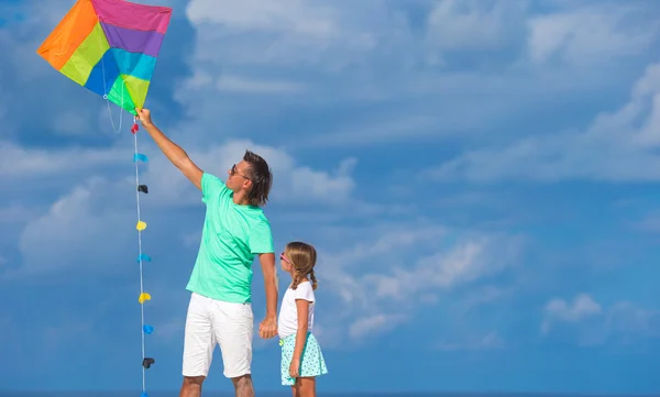 Glücklicher Vater und kleines Mädchen fliegen gemeinsam Drachen am tropischen Strand — Stockfoto