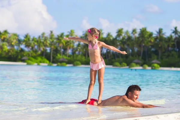 Kleines Mädchen am Strand übt Surfposition auf ihrem Vater — Stockfoto