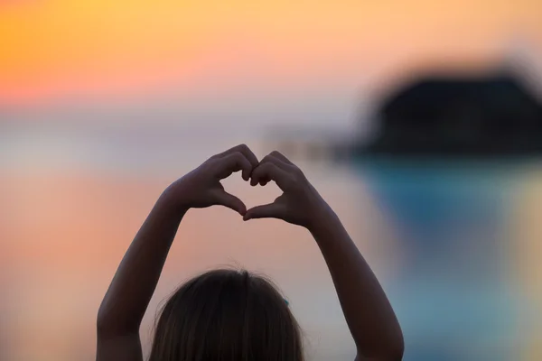Silhueta de coração feita por crianças mão ao pôr do sol — Fotografia de Stock