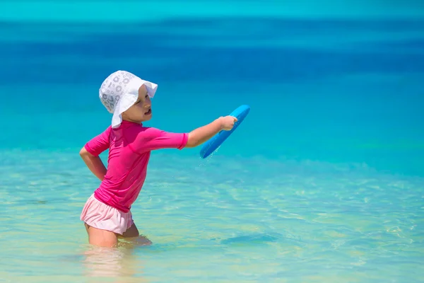 Kleines Mädchen spielt mit fliegender Scheibe am weißen Strand — Stockfoto
