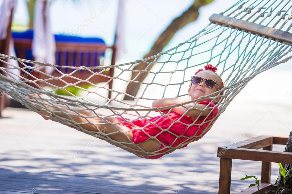 Cute little girl on tropical vacation relaxing in hammock