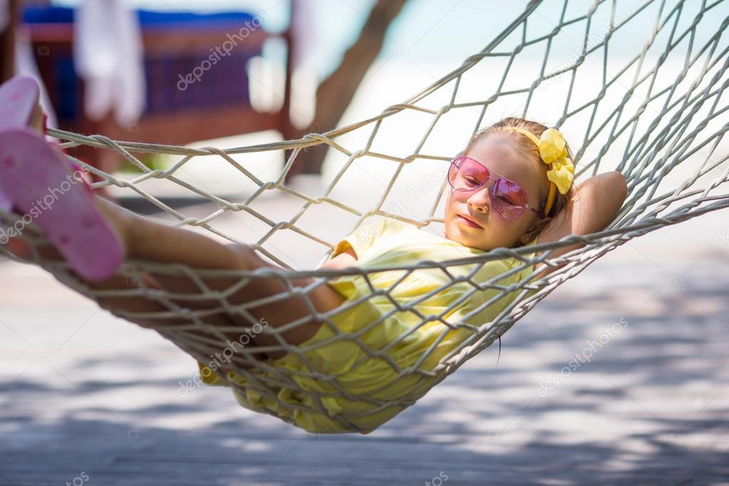 Little girl on tropical vacation relaxing in hammock