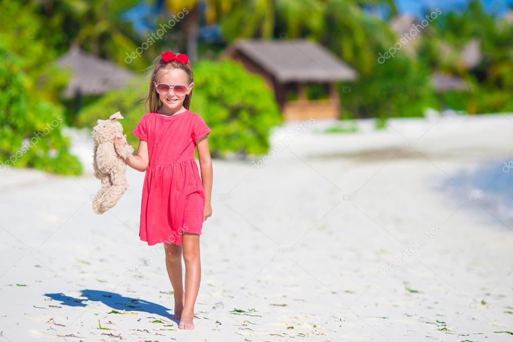 Adorable little girl playing with plush toy on beach