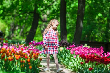 Lale bahçesinde çiçekli küçük sevimli kız 