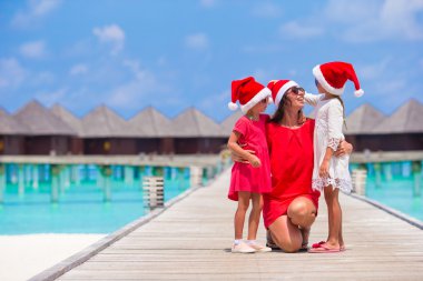 Mutlu anne ve kızıyla su villa yaz tatilde yakınındaki Santa şapkalı