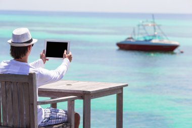 Tablet bilgisayar açık café'de yaz tatili içinde olan genç adam