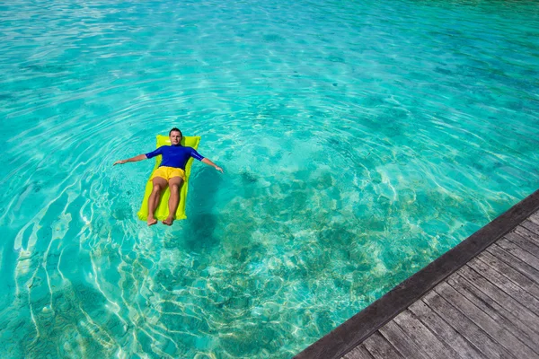 Jonge gelukkig man ontspannen op opblaasbare matras in de zee — Stockfoto