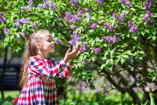 Adorable happy little girl with basket in lilac flower garden — Stock Photo, Image