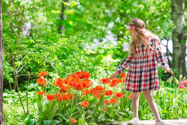 Pequena menina adorável com flores no jardim tulipas — Fotografia de Stock