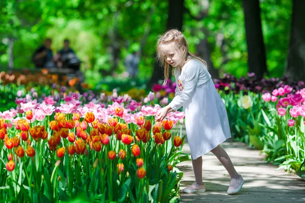 Маленькая красивая девочка в саду тюльпанов в теплый весенний день — стоковое фото