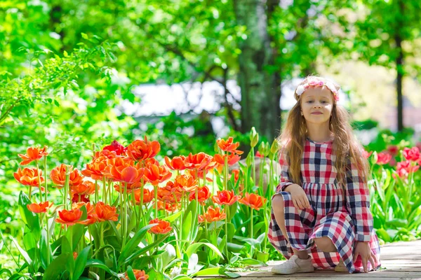 Kleines schönes Mädchen im Tulpengarten an einem warmen Frühlingstag — Stockfoto