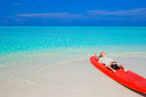 Junge Surferin am weißen Strand auf rotem Surfbrett — Stockfoto