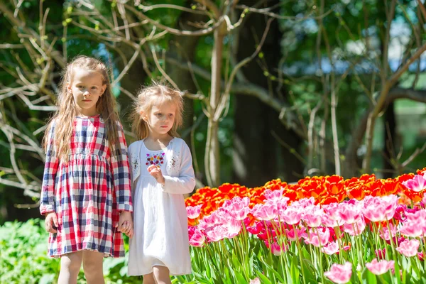 Kleine entzückende Mädchen, die im üppigen Tulpengarten spazieren gehen — Stockfoto