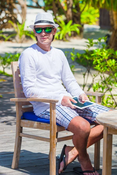 Hombre joven con tableta en la playa tropical — Foto de Stock